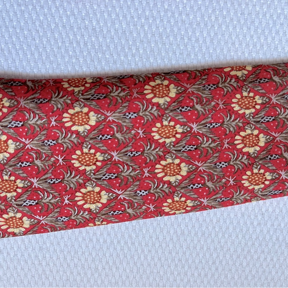 Preowned Hermes silk tie. Burnt orange with sunflowers and pineapple trees.